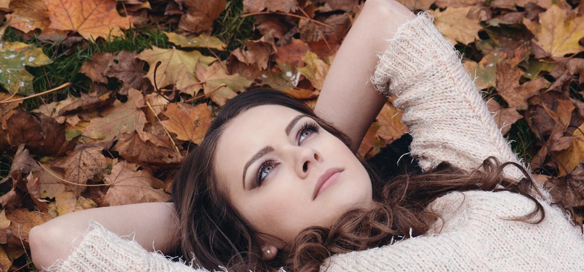 woman laying in leaves, day dreaming