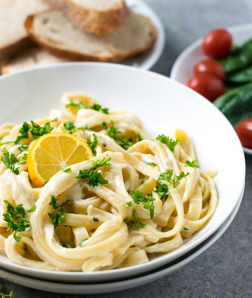 bowl of pasta with lemon sauce and a side of tomatoes 